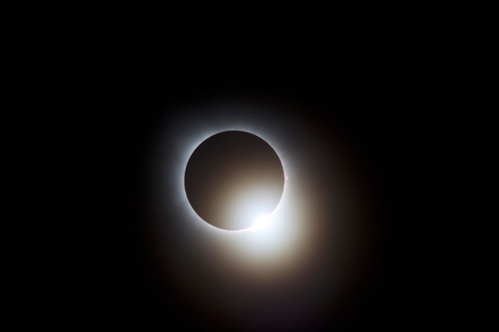 Solar eclipse image shows the sun nearly completely covered, but not quite. A tiny arc of the sun is uncovered to produce what looks like a diamond ring.